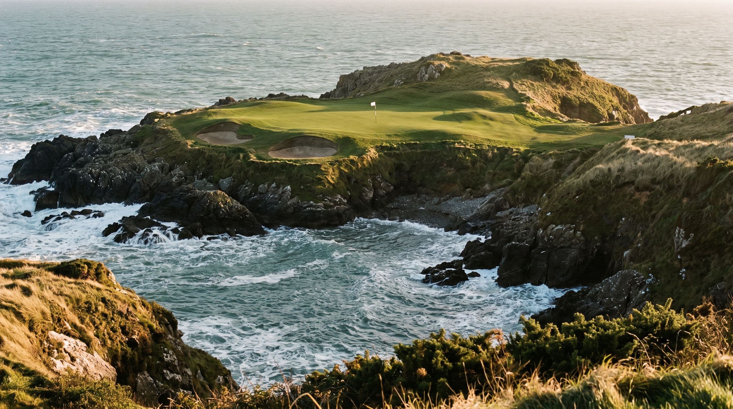 A par three played across a rocky sea inlet to a small green on the far headland.